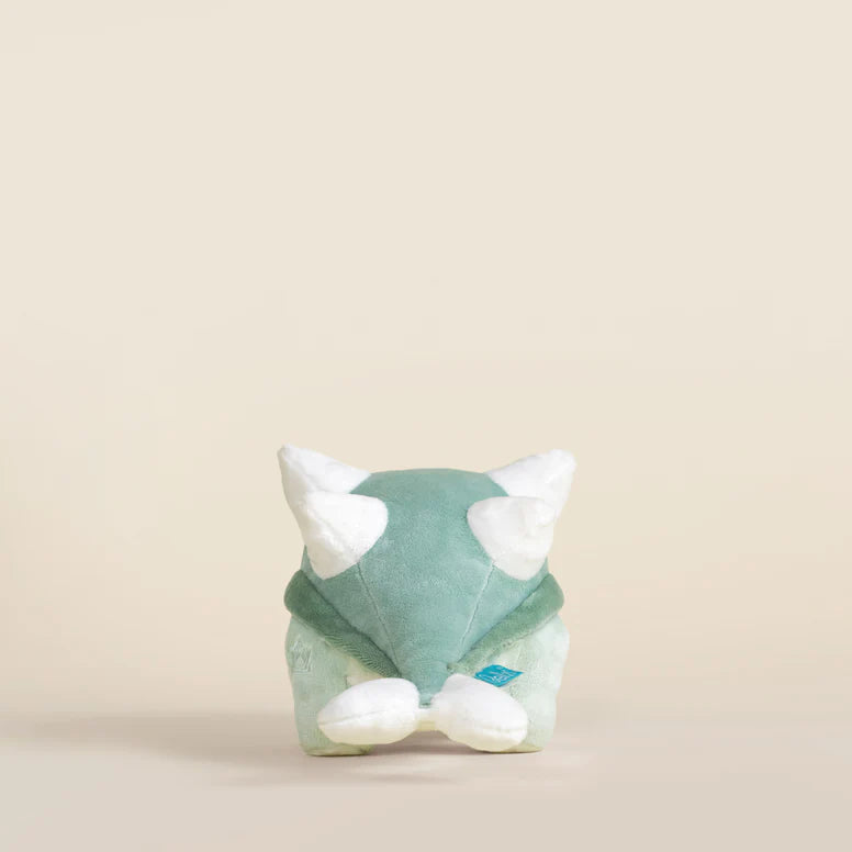 Plush toy ankylosaurus dinosaur with a light green body and white accents on a beige background