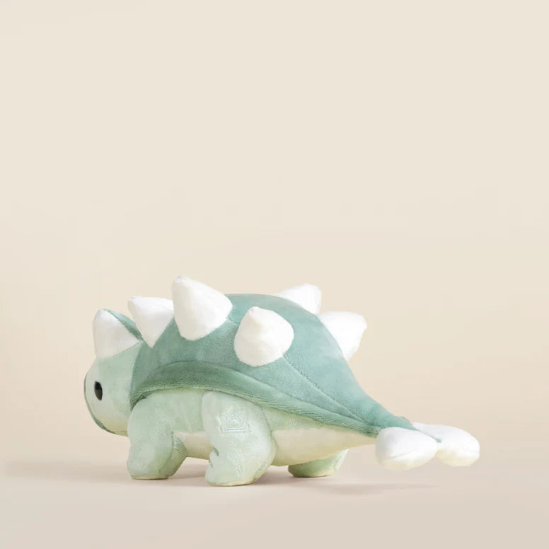 Plush toy ankylosaurus dinosaur with a light green body and white accents on a beige background