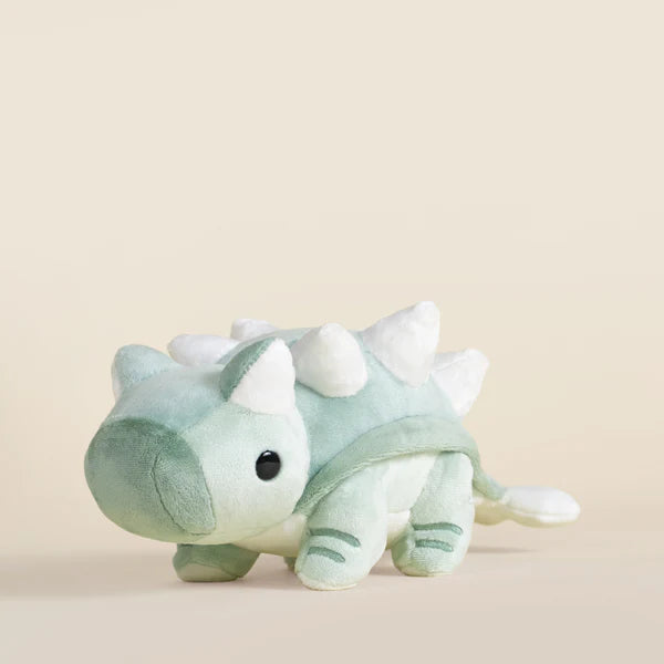 Blue plush toy ankylosaurus dinosaur on a beige background.