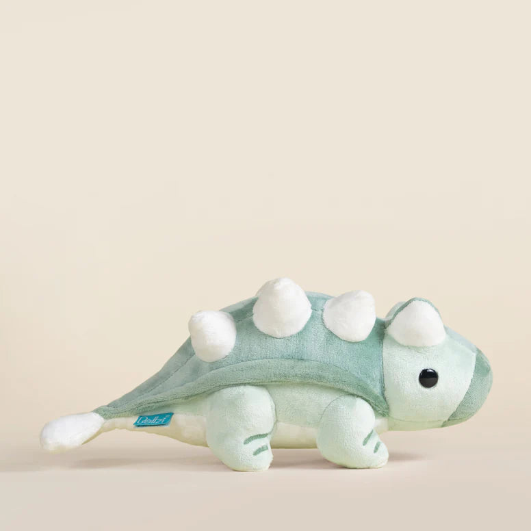 Plush toy ankylosaurus dinosaur with a light green body and white accents on a beige background