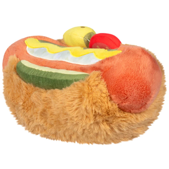 Plush toy shaped like a hot dog with mustard, ketchup, and a pickle on a white background